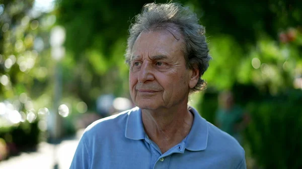 One happy older man walking outside during sunny day, pensive contemplative senior