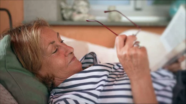 Older Woman Reading Book Senior Person Laid Putting Reading Glasses — Stok Foto