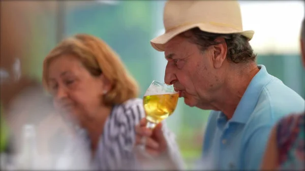 Older man drinking beer, candid senior drinks draft beer at restaurant