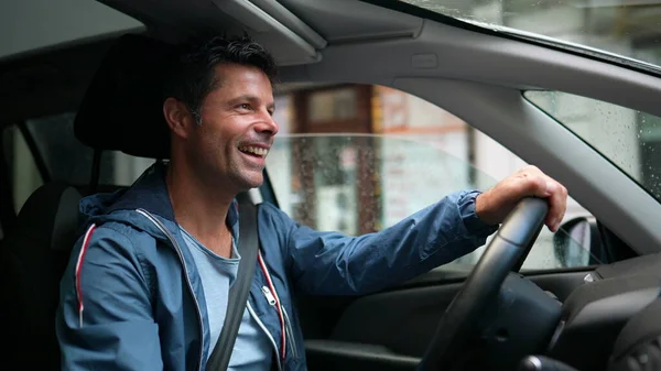 Happy driver holding steering wheel driving in city