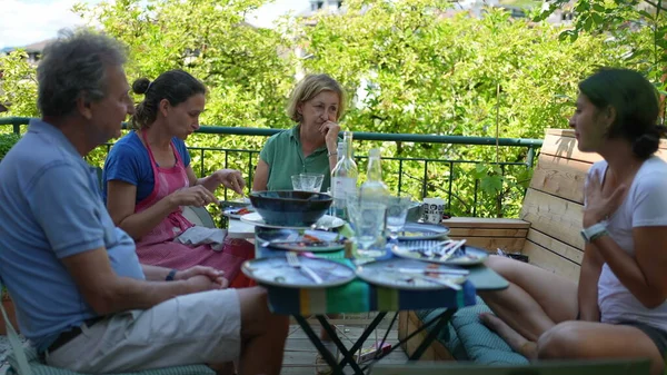 Family sitting at table during lunch outside in conversation during summer day
