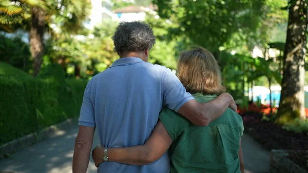 Back of senior couple walking outside in green city Back of senior couple walking outside in green city