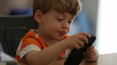 Çocuk telefonu teknolojiyle tutuyor.