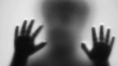 Çocuk, tek renkli camlara vurarak yardım ve depresyon kavramını destekliyor.