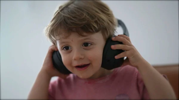 Child removing headphones from ear kid taking takes off headphones