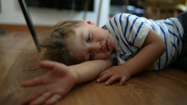 Sıkılmış küçük çocuk evde yerde yatıyor. Yapacak bir şeyi yok.