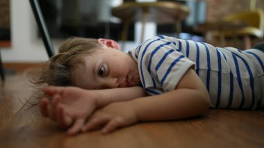 Bored kid Child feeling boredom lying on floor at home with nothing to do