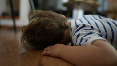 Bored kid Child feeling boredom lying on floor at home with nothing to do