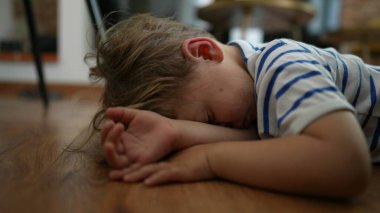 Bored kid Child feeling boredom lying on floor at home with nothing to do