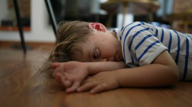 Bored kid Child feeling boredom lying on floor at home with nothing to do