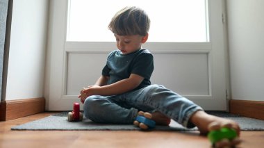 Küçük çocuk parke zeminde oyuncaklarla oynuyor.