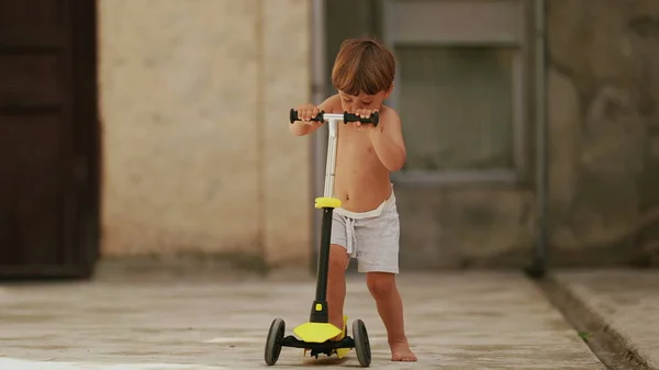 Kid rides toy scooter in sunny day activity