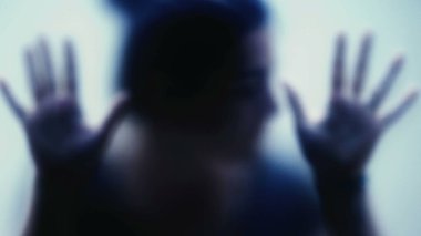 Camın arkasına sıkışmış depresyon konseptini destekleyen ve yardım isteyen depresyonlu bir kadın.