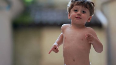 Dışarıda kameraya doğru koşan sevimli küçük çocuk.