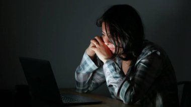 Geceleri dizüstü bilgisayarın önünde içeriği okuyan kişi