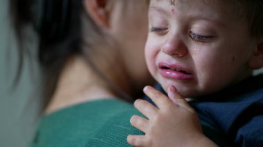 Ağlayan küçük bir oğlan çocuğu teselli eden bir anne.