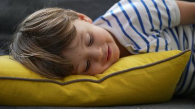 Sevimli küçük bir çocuk kanepede yatıyor. Sevimli bir çocuk.