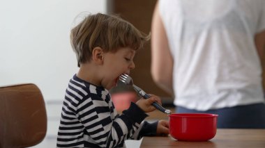 Bir çocuk tek başına çatal tutarak meyve yiyor.