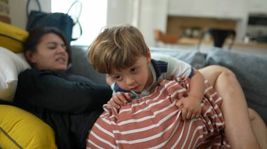Anne ve küçük çocuk evdeki kanepede rahat ve gerçek hayatta oturuyor.