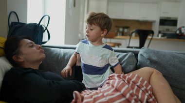 Anne ve küçük çocuk evdeki kanepede rahat ve gerçek hayatta oturuyor.