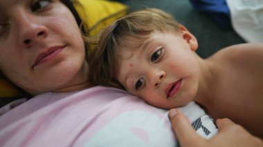 Anne ve çocuk kanepede uzanmış, dinleniyor. Küçük çocuk annesiyle birlikte kanepede yatıyor.