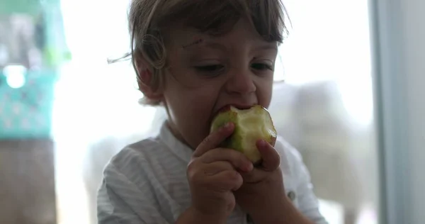 Toddler boy taking a bite of apple fruit healthy snack