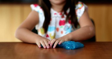 Küçük kız sümüksü plastikle oynuyor Mavi balçık ile bir baloncuk yaratıyor