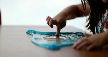 Yakın plan çocuk elleri mavi plastik yapışkanla oynuyor.