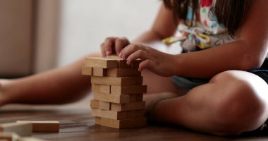 Child playing with wooden building blocks. Kid trial and error play
