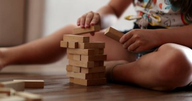Child playing with wooden building blocks. Kid trial and error play