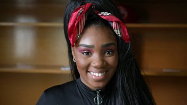 Kameraya gülümseyen siyah bir genç kız portresi.