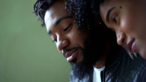 A young black couple looking at phone screen together