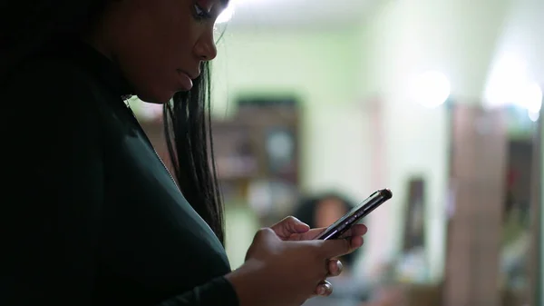 A teen girl looking at cellphone device at home an african teenager holding phone