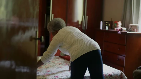 Senior African Woman Tidying Room Removing Clothes Bed Organizing Housework —  Fotos de Stock