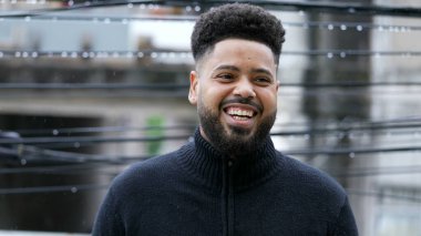 Çiselemede dikilen Brezilyalı genç bir adam kamera portresine gülümsüyor.