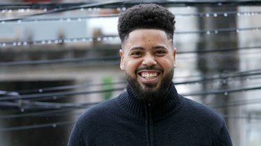 Çiselemede dikilen Brezilyalı genç bir adam kamera portresine gülümsüyor.