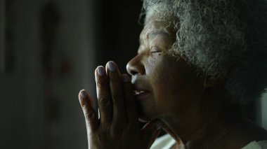 Yaşlı bir Afrikalı kadın Tanrı 'ya dua ediyor. Umut ve inançla gözlerini kapıyor.