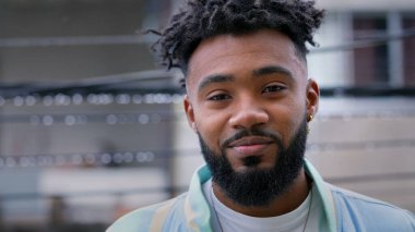 Dışarıda çiseleyen yağmurda kameraya gülümseyen mutlu genç bir Brezilyalı.