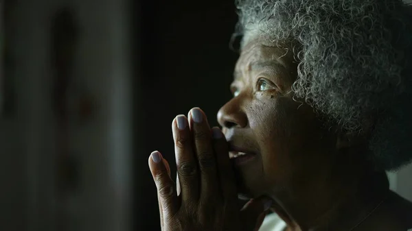 An older African woman praying to God closing eyes with HOPE and FAITH