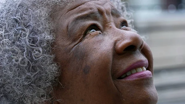 An African woman opening eyes to sky smiling with HOPE