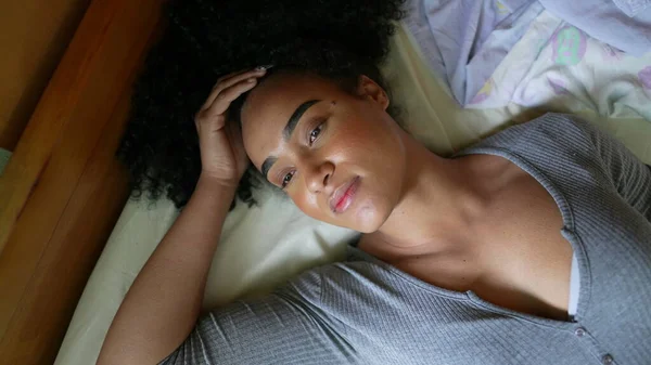 An African woman lying down in bed to rest