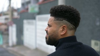 Düşünceli genç bir adam şehir sokaklarında yürüyor.