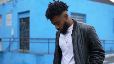 Düşünceli genç bir siyah adam şehir sokağında yürüyor düşünceli bir Afrikalı.