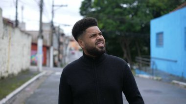 Kentsel caddede ilerleyen çeşitli siyahi bir adam.