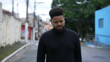 Kentsel caddede ilerleyen çeşitli siyahi bir adam.