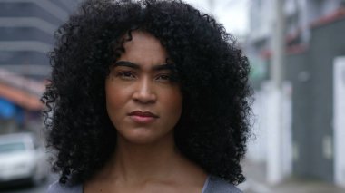 A confident black woman standing outside looking at camera