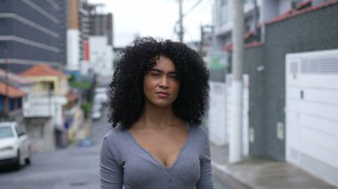 A confident black woman standing outside looking at camera