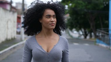 A confident black woman standing outside looking at camera