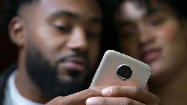 Two people looking at cellphone device close-up faces staring at phone