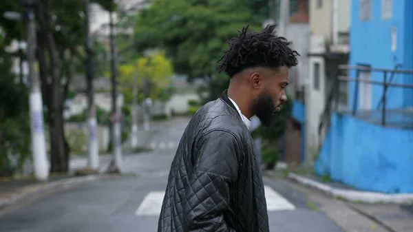 A pensive person walking outside in street one Brazilian man walks forward